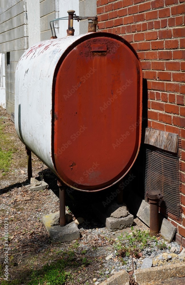 Older home heating oil fuel tank standing on concrete slabs.