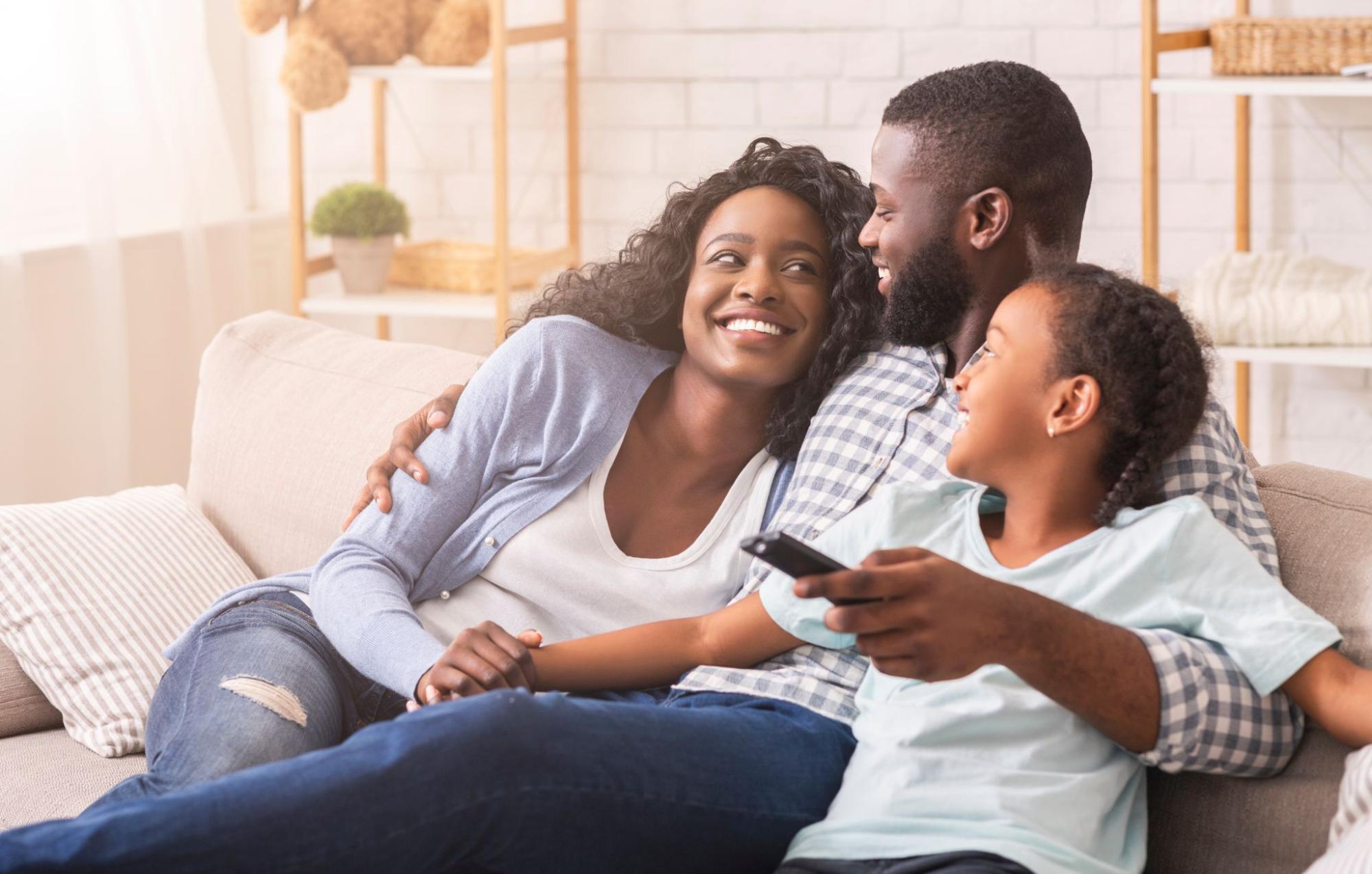 Happy family sitting on the couch, watching tv, enjoying their clean, indoor air 