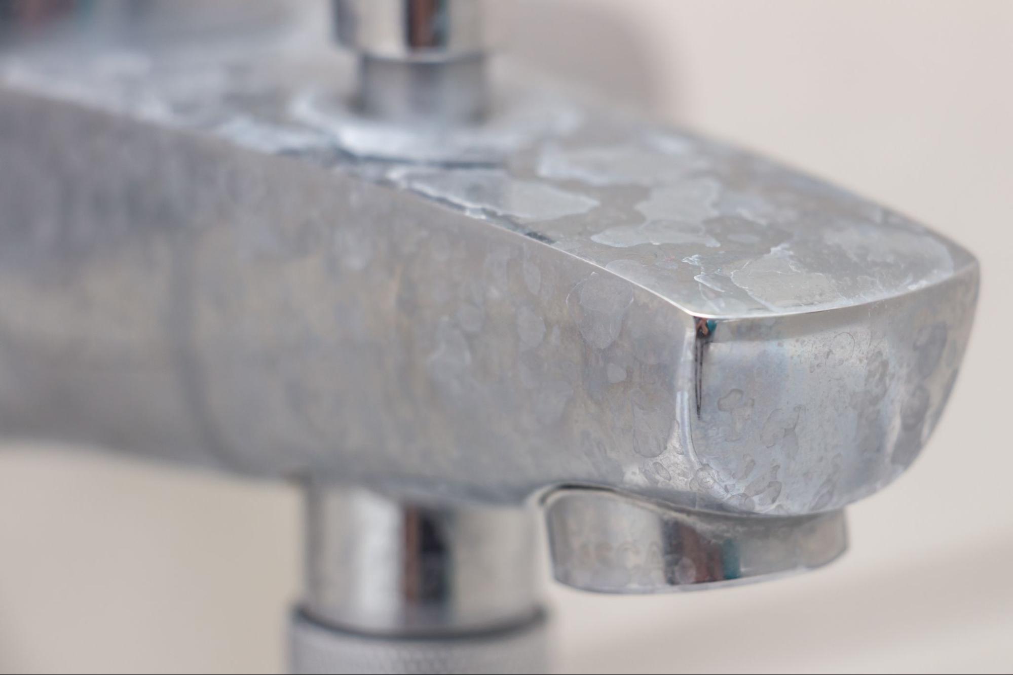 Close-up of faucet with limescale, white chalky deposit and stains. Formed on the plumbing system by a combination of soap residues and hard water. 