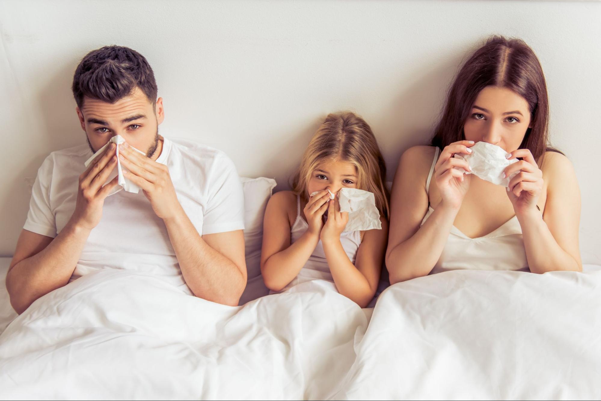 Family in bed with tissues suffering from poor indoor air quality 