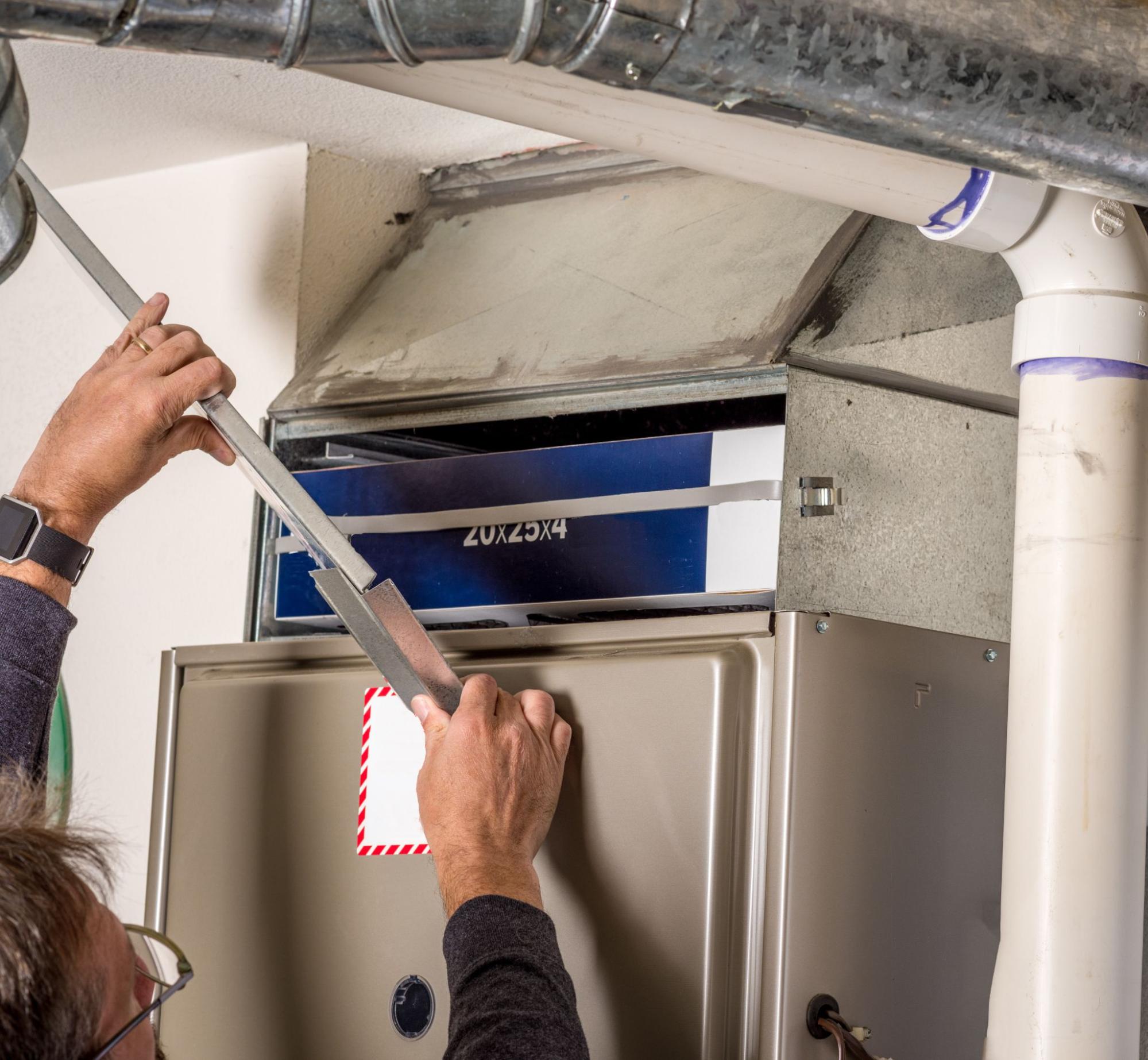 Handyman removes furnace panel cover to perform routine HVAC maintenance