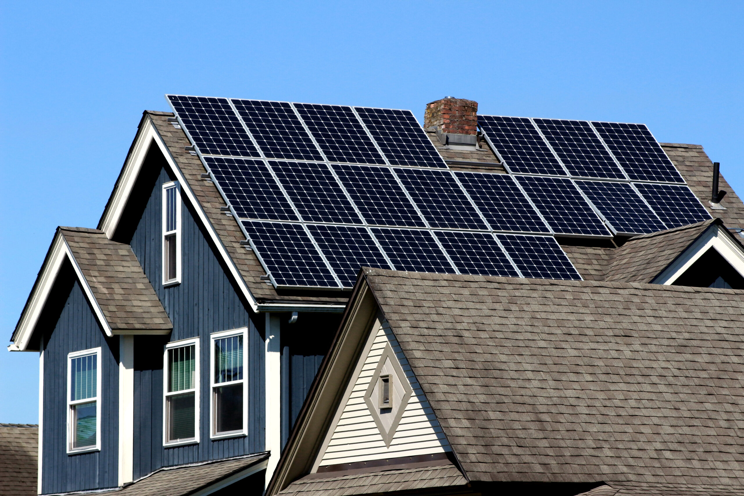 Solar Panels installed and in use on the roof of a blue home.