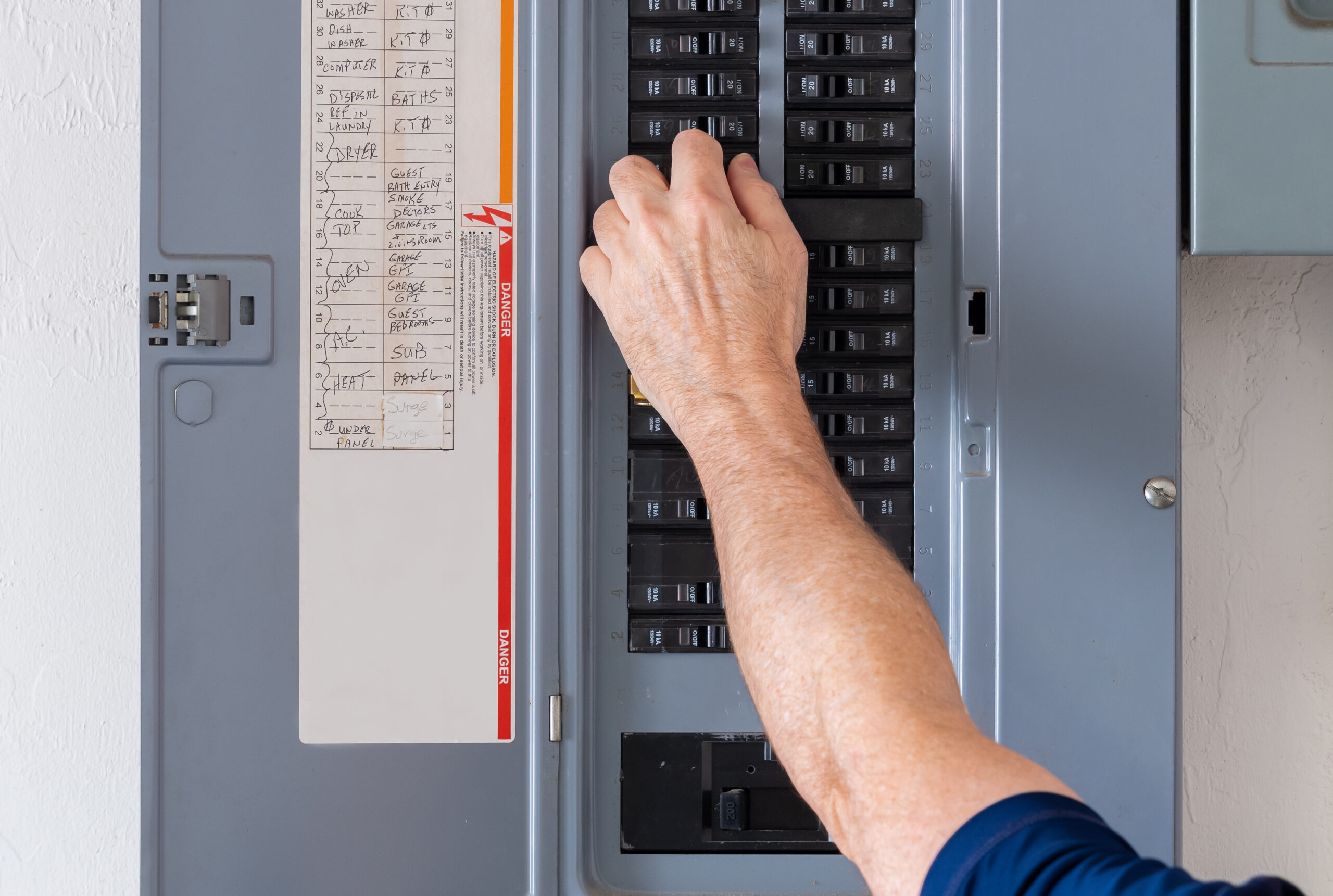 Resetting tripped breaker in residential electricity power panel. Electrician turning off power for electrical outlet at circuit breaker box.