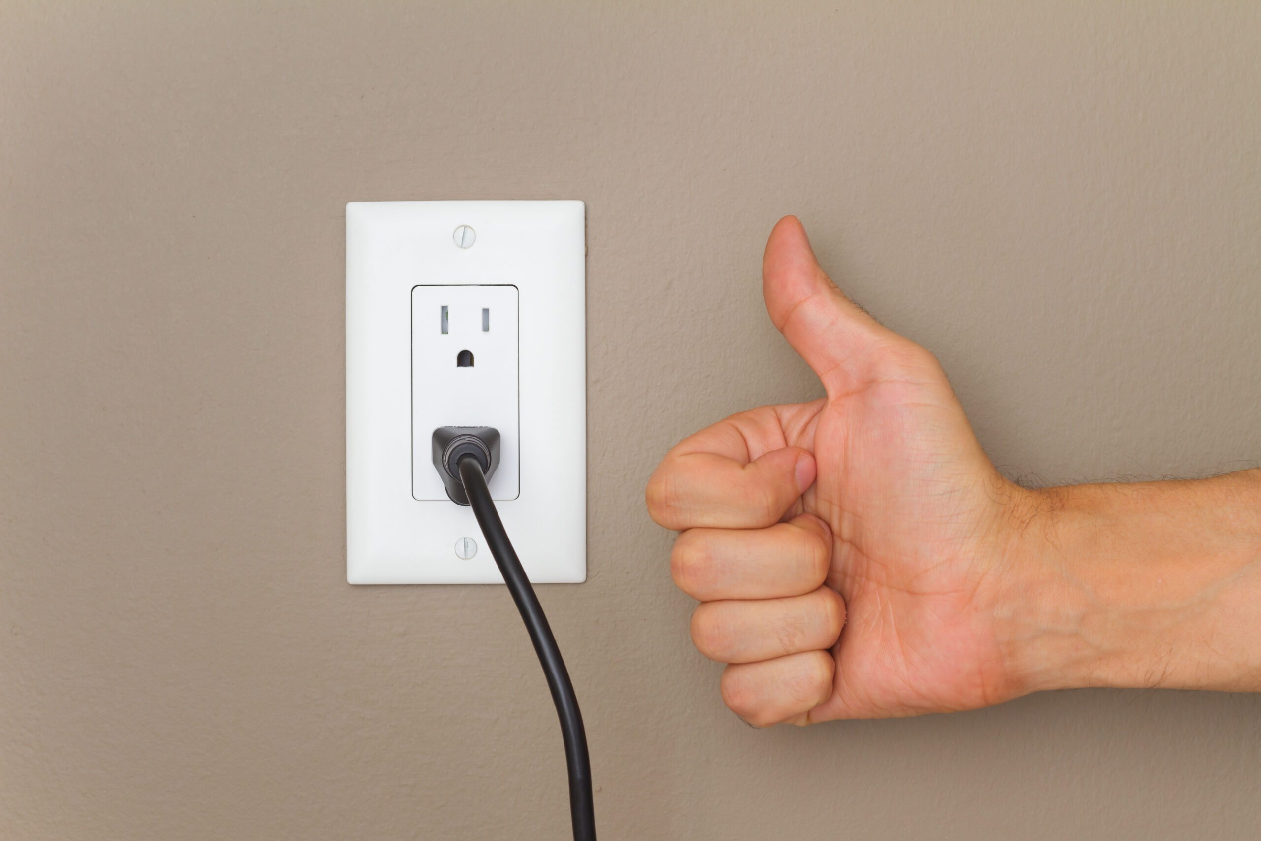 Wall outlet with something plugged in and a thumbs up