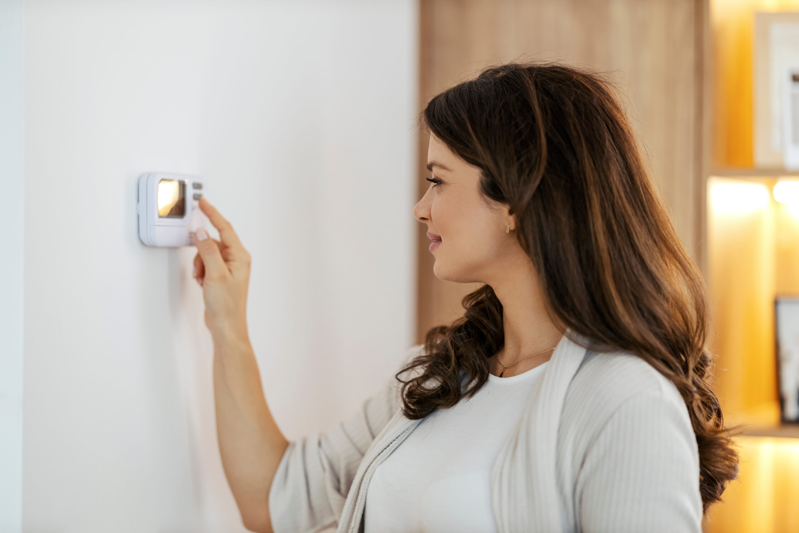 Woman is checking to see if her thermostat is working properly