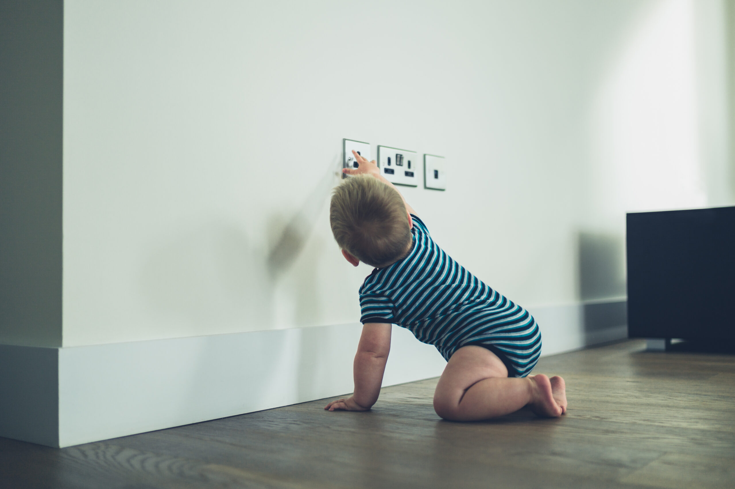 little baby reaching for electrical outlet, childproofing, electrical safety