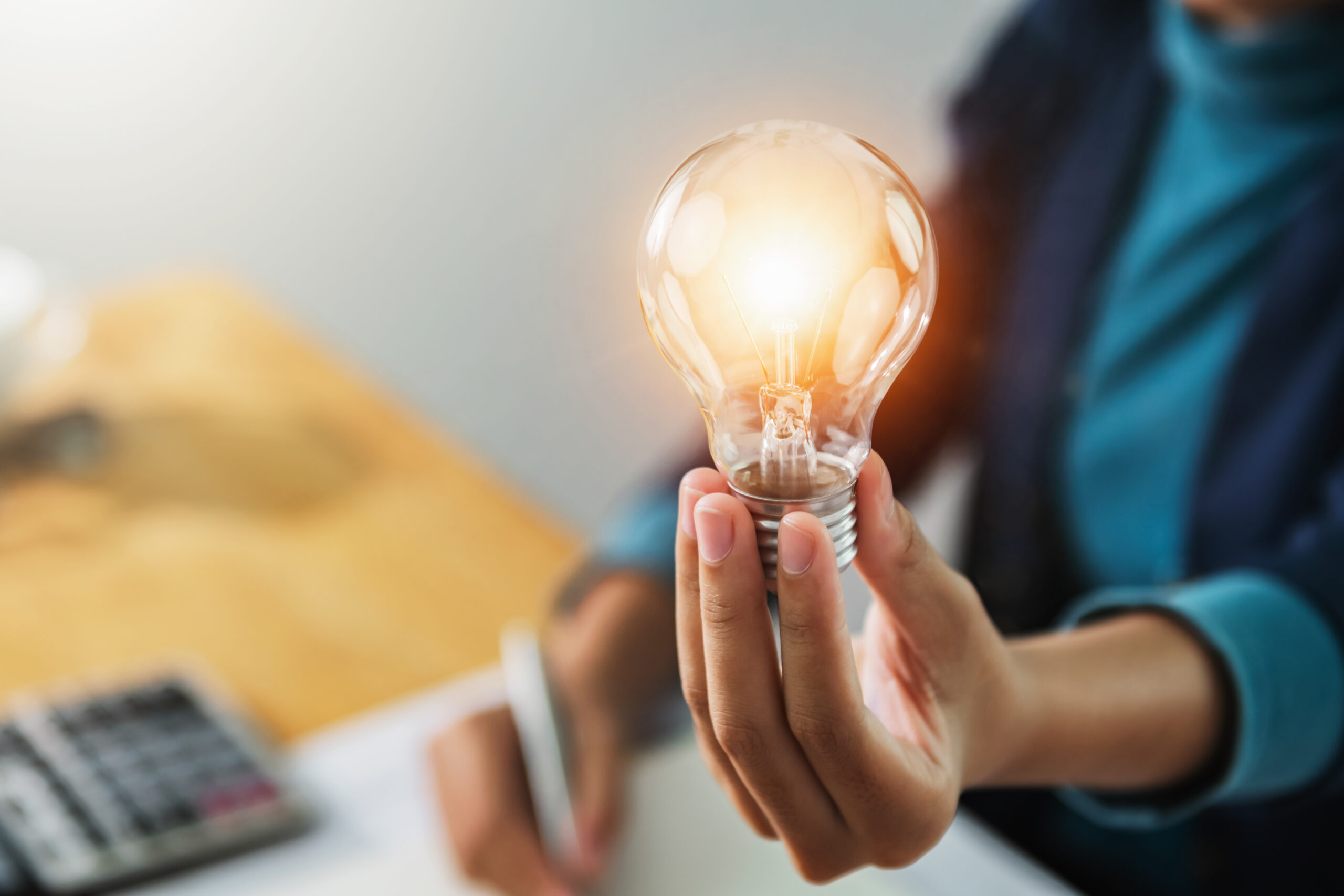 Hand holding an illuminated light bulb