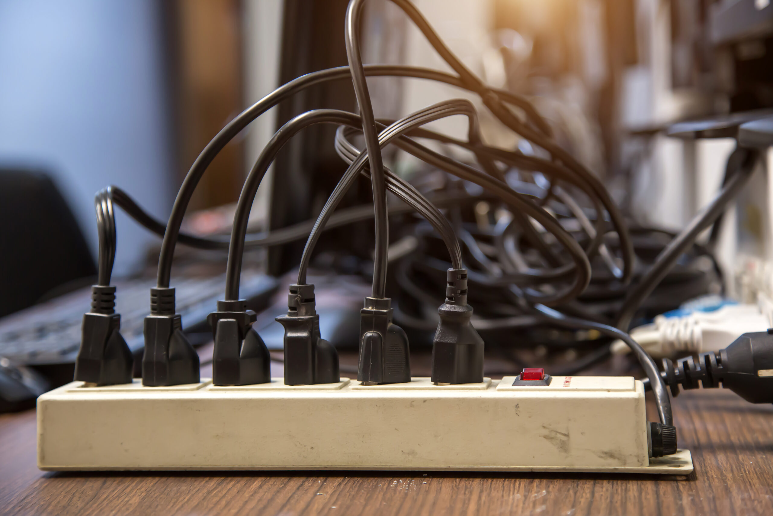 Old and damaged electric surge protector has many appliances plugged in - risk danger overloaded circuits